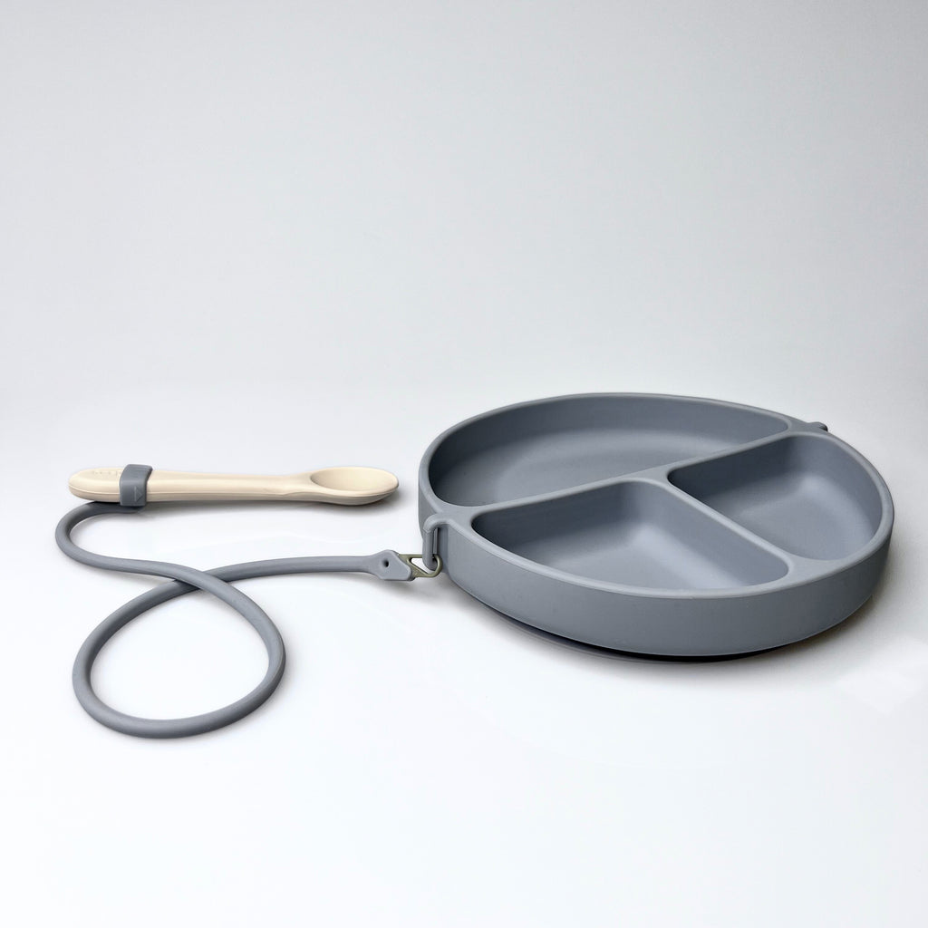 Gray divided plate with a wooden spoon on a white background