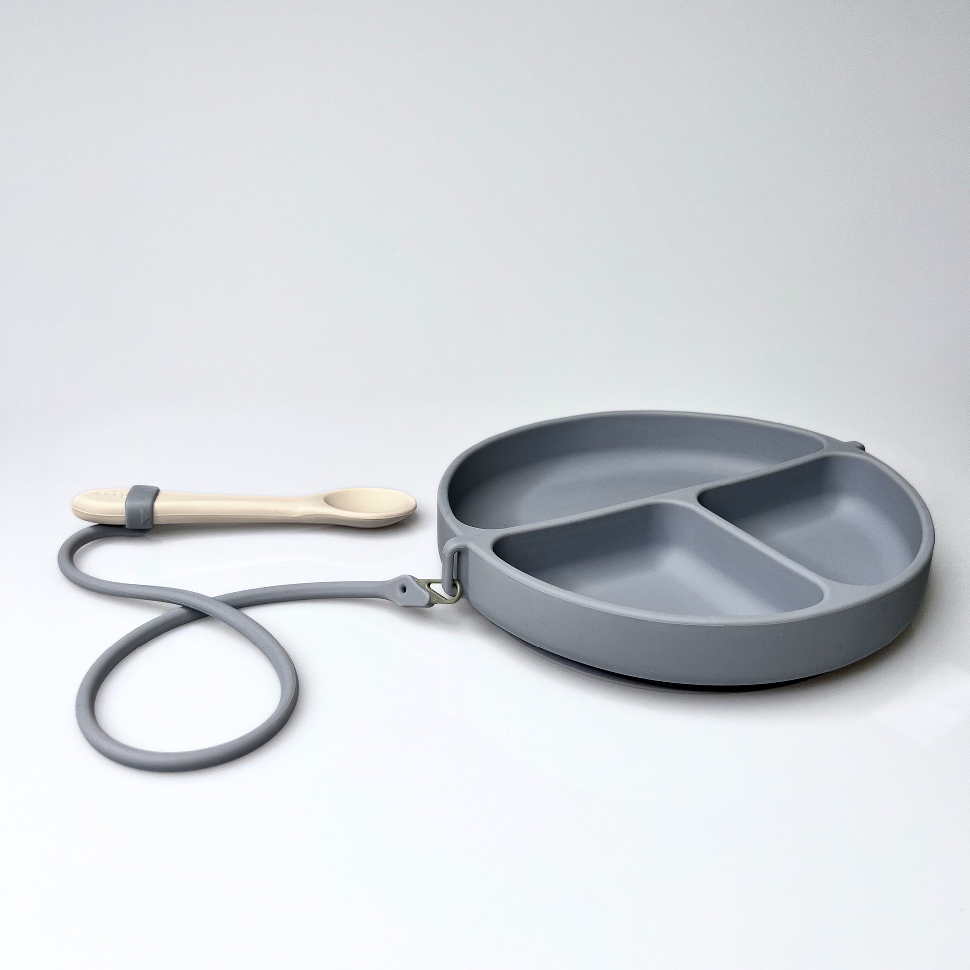 Gray divided plate with a wooden spoon on a white background