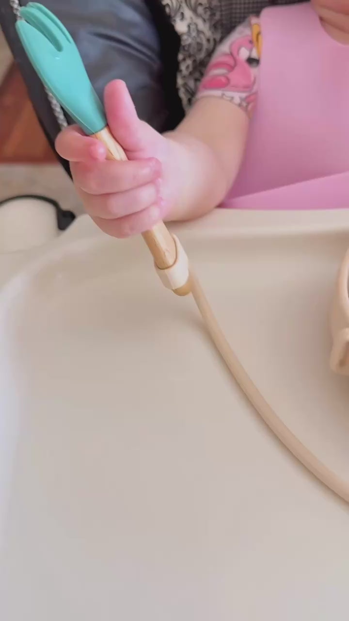 A white american toddler girl using a beige dropless plate dropping her spoon amazon video